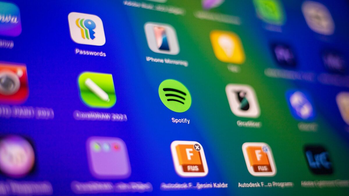 Écran d'appareil numérique avec grille d'icônes d'applications (Spotify, Passwords, CorelDRAW 2021) sur fond bleu-vert flou.