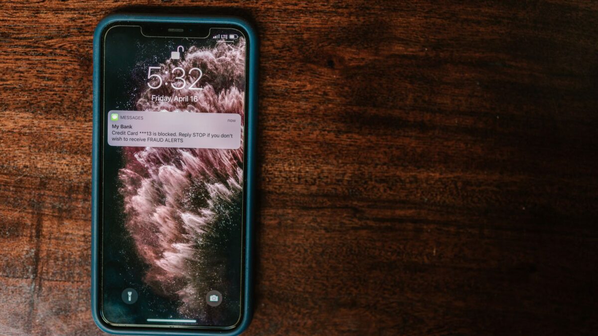 Smartphone sur table en bois, affichant une notification de banque sur un avertissement de fraude de carte de crédit.